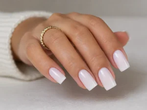 Main avec ongles longs carrés au fini blanc laiteux