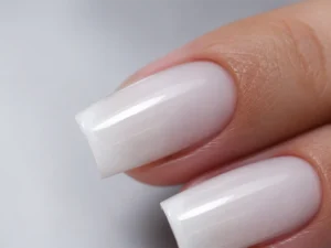 Gros plan sur deux ongles longs carrés au fini blanc laiteux