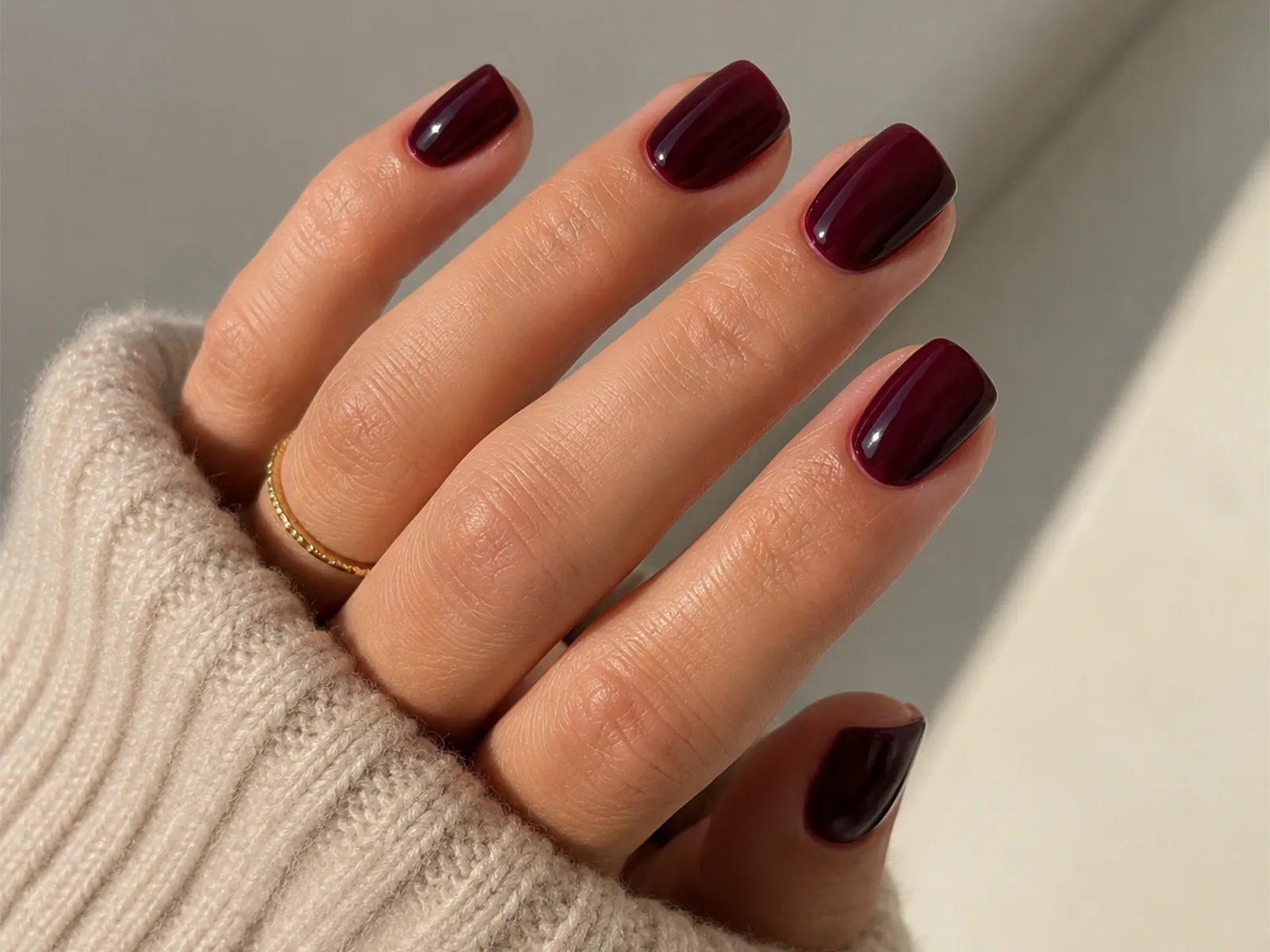 Main avec manucure bordeaux sur ongles courts